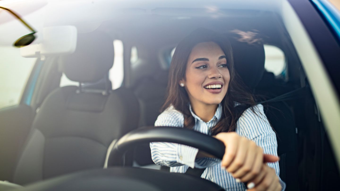 Smiling Woman Driving a Car in Daylight